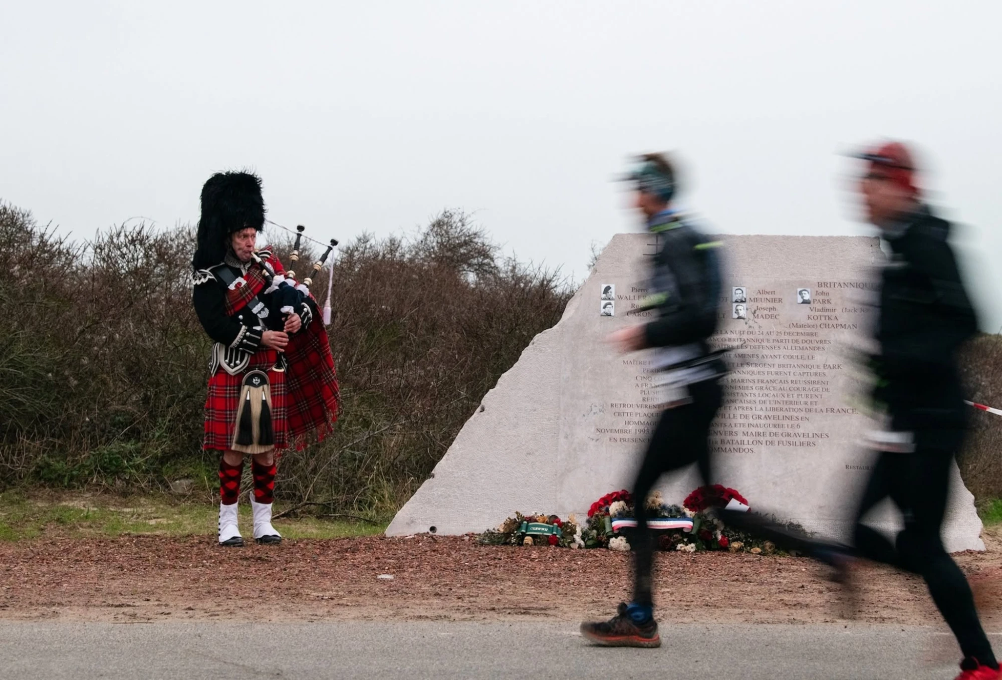 Joueur de cornemuse près du mémorial, coureurs en arrière-plan